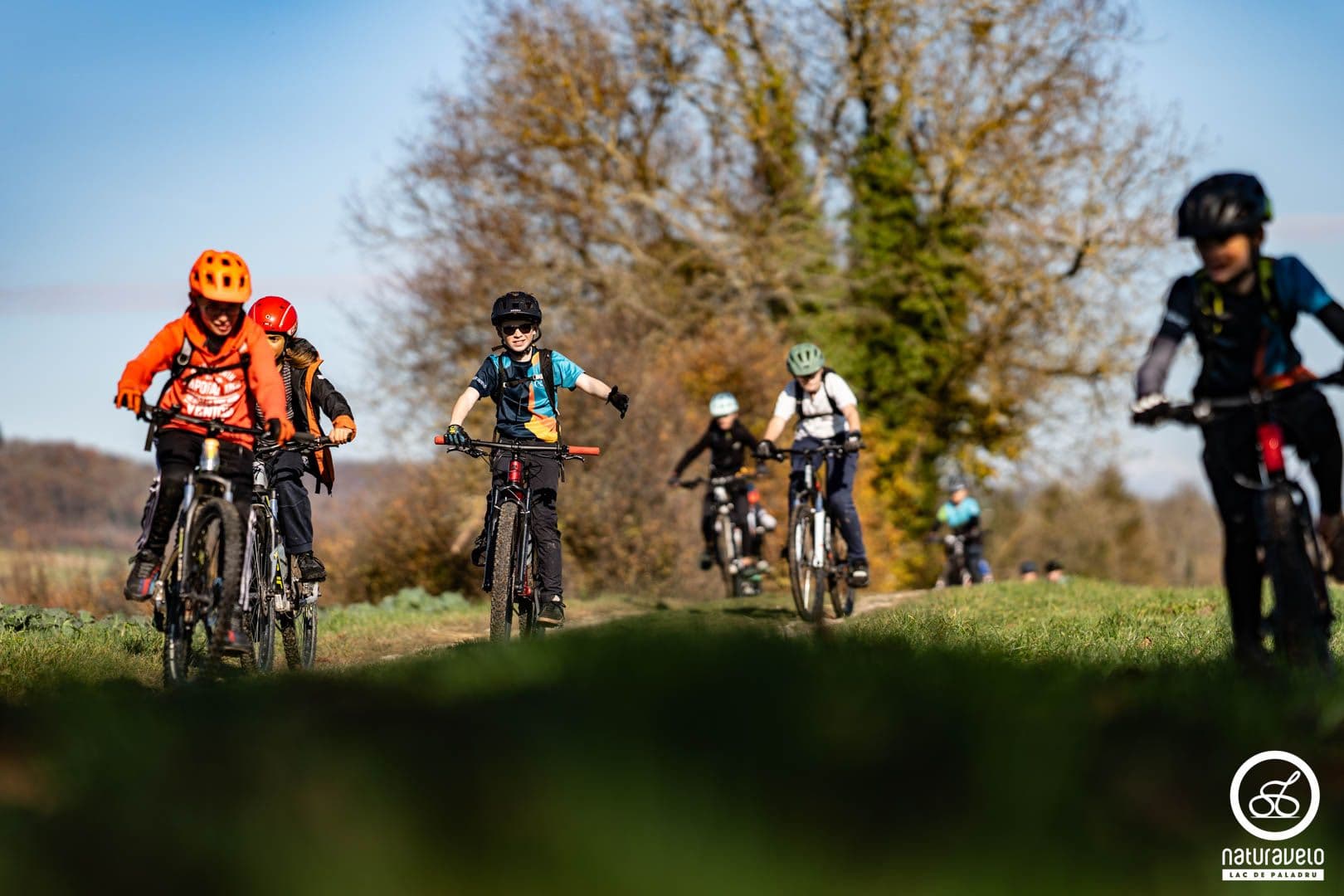 Jeunes vététistes de l'école VTT roulant ensemble sur un chemin ensoleillé